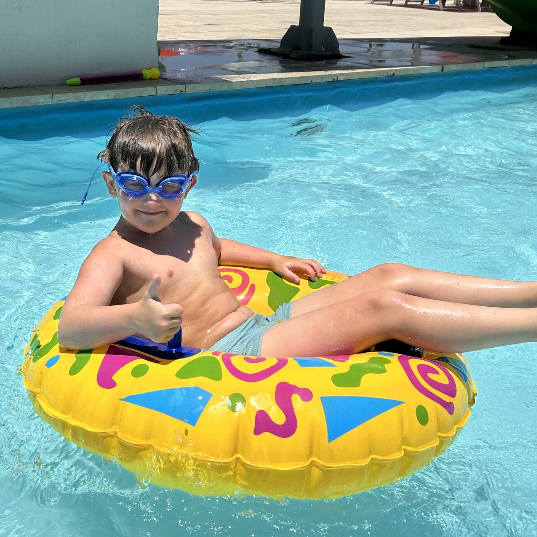 Travis from autism family travel guide is in a rubber ring in a swimming pool looking happy.