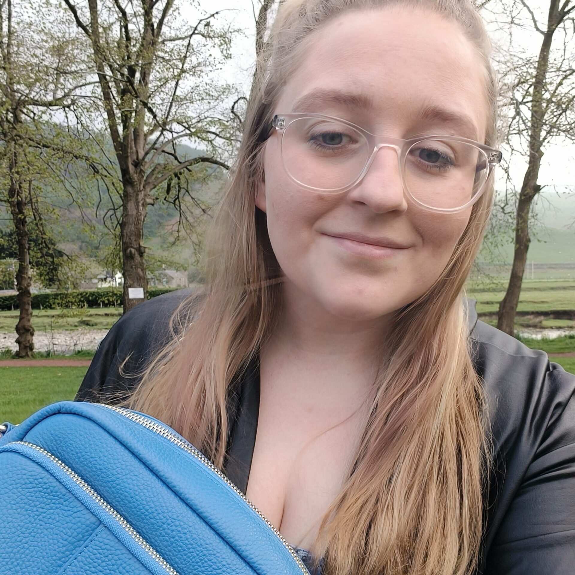 Natasha from autism family travel guide is holding a blue crossbody travel bag.